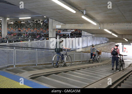 Interior of a new multi-storey bike park in Cambridge, UK. Shows users on the access ramp with shallow steps and bike ramps Stock Photo