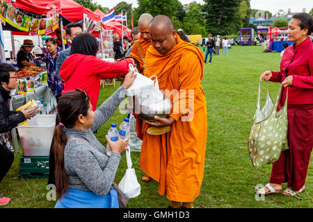 Thai People Offer Food To Two Monks At The Brighton Thai Festival, Preston Park, Brighton, Sussex, UK Stock Photo
