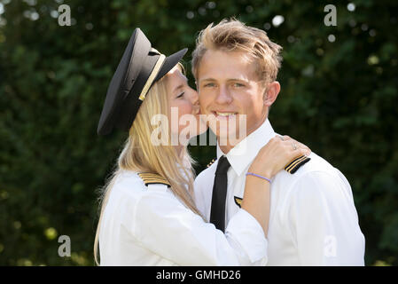 Portrait of two young male and female airline officers in uniform kissing Stock Photo