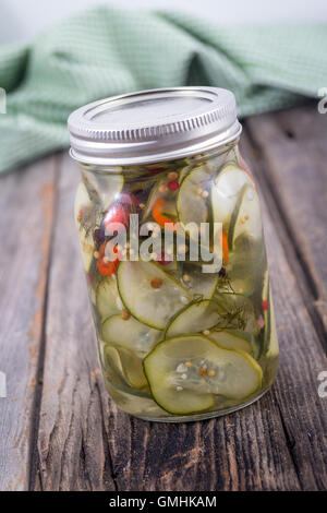 pickled cucumber jar with spices and hot pepper on wood table Stock Photo