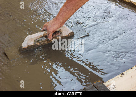 hand spreading poured concrete and leveling concrete with trowel Stock Photo