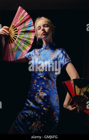 girl in japanese costume dancing with fans on black background Stock Photo