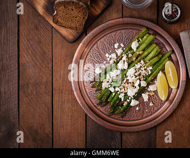 Warm salad of roasted asparagus, feta cheese, nuts, flavored with lemon juice. Top view Stock Photo
