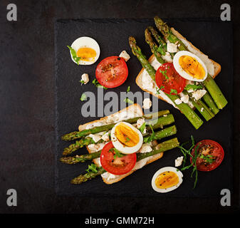 Sandwiches with caramelized asparagus, feta cheese, tomatoes and eggs. Top view Stock Photo