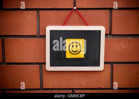 Paper note with happy face on blackboard. Close up. Stock Photo