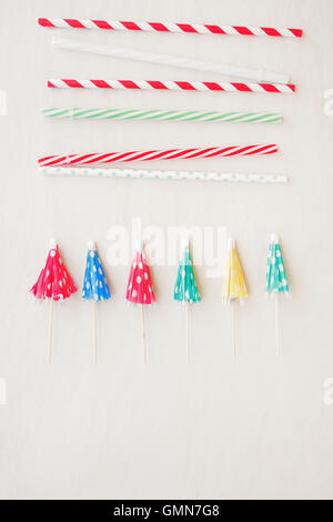Drinking straws and mixed paper cocktail umbrellas background. Top view, blank space Stock Photo