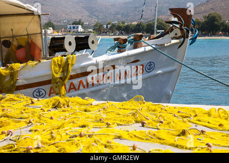 A Greek fishing boat in the harbour at Ormos,Amorgos.The nets are laid out on the harbour to untangle them and remove items Stock Photo