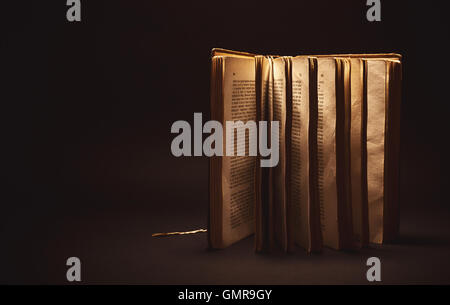Conceptual composition, opened old book on black background. Stock Photo