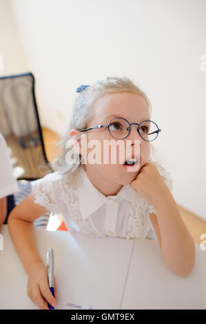 Small schoolgirl of an elementary school sits at a school desk in ...