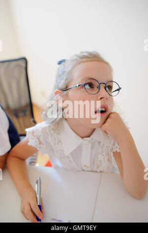Small schoolgirl of an elementary school sits at a school desk in ...