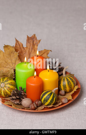 Fall holidays - Halloween and Thanksgiving. Still life - candles and pumpkins, pine cones, nuts, leaves. Stock Photo