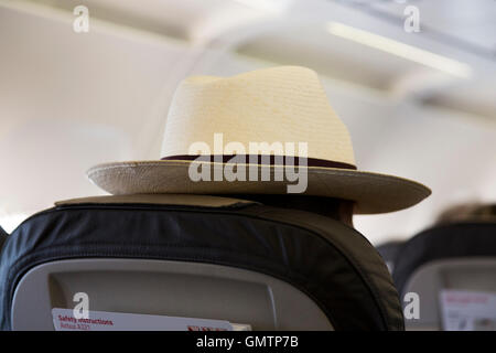 Plane passenger / man / person flying ' incognito ' by wearing a panama hat on an airplane / aeroplane / aircraft flight. Stock Photo
