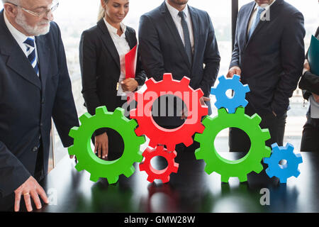 Business people assembling cogwheels, teamwork concept Stock Photo
