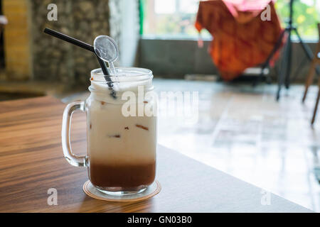 Iced chocolate with milk in retro glass jar (Mason Jar) on wooden table in cafe. Stock Photo