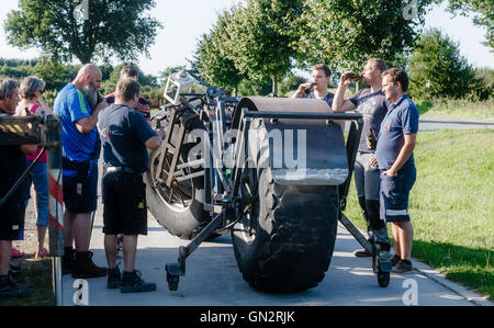 Rade, Germany. 27th Aug, 2016. Friends and neighbours look on at Frank Dose who will for the first time ride his built-bicycle, which he wants to set the Guinness Book record for 'the most heaviest wheeled bicycle in the world' in Rade, Germany, 27 August 2016. The vehicle currently weighs 940 kg on the scale but can potentially increase to around 1.2 tonnes. Photo: Markus Scholz/dpa/Alamy Live News Stock Photo