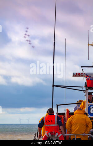 Rhyl, Denbighshire, Wales, UK. 28th August 2016. Rhyl Air Show – The annual air show at Rhyl seafront with the RAF Red Arrows. Rhyl lifeboat and crew watch the Red Arrows fly by Stock Photo