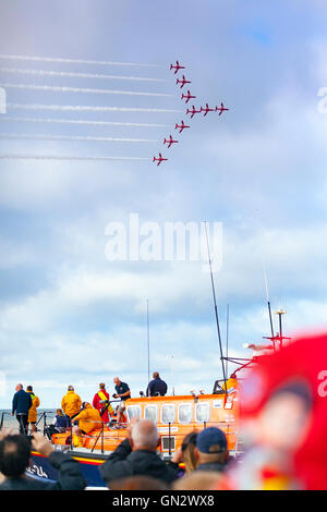 Rhyl, Denbighshire, Wales, UK. 28th August 2016. Rhyl Air Show – The annual air show at Rhyl seafront with the RAF Red Arrows. Crew of the Rhyl Lifeboat watch the Red Arrows fly by. Stock Photo