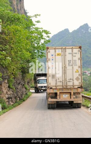 Tinh Tuc, Vietnam - 20 April 2011. Two large trucks meet on narrow mountain road with insufficient room to pass each other. Stock Photo