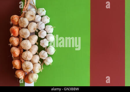 Onions and garlic in a bundle on bright multi-colored stone wall Stock Photo