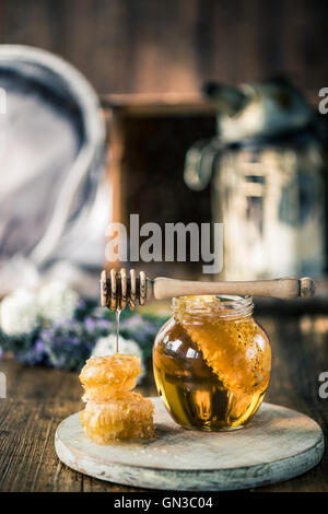 Honey dripping over vax comb on wooden table Stock Photo