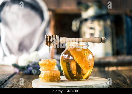 Honey dripping over vax comb on wooden table Stock Photo