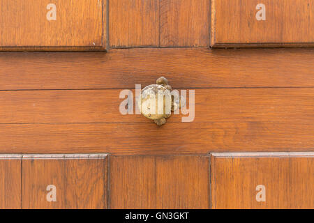 Close view of a round metal door knob. Light brown wooden door. Stock Photo