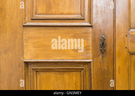 Old light brown wooden door with decorative metal key hole. Stock Photo