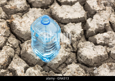 Bottle with water on the dried ground. Stock Photo