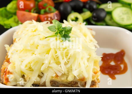 Lasagna portion served with fresh vegetables close up Stock Photo