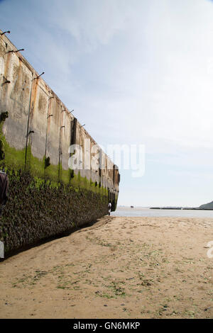 Remnants of a moss-covered Mulberry harbor sits on the beach at Arromanches-les-Bains, known as Gold Beach during D-Day. Stock Photo