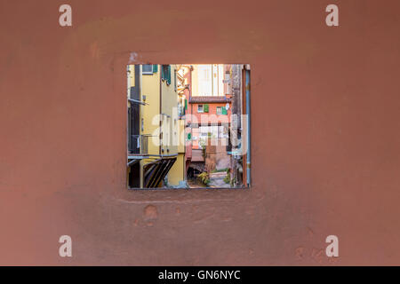 Old water canal hidden behind a window in Bologna downtown in Italy Stock Photo