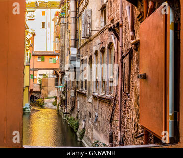Old water canal hidden behind a window in Bologna downtown in Italy Stock Photo