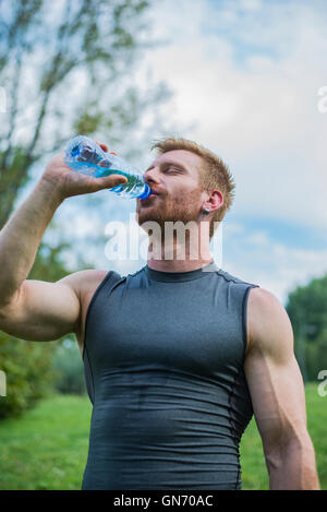 Muscular man drink water from blue bottle in the gym Stock Photo - Alamy