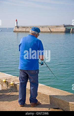 Old man in blue shirt fishing from the quayside at Les Sables D'Olonne in the Vendee region Stock Photo