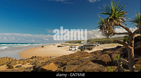 Panoramic view of vast 75-mile beach, ocean & rocks near Indian Head on Fraser Island with vehicles on unusual highway, blue sky Stock Photo