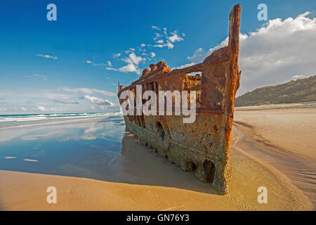 Coastal landscape with rusting remains of historic Maheno shipwreck on sandy 75-mile beach under blue sky on Fraser Island Australia Stock Photo
