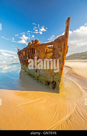 Rusting remains of historic Maheno shipwreck on sandy 75-mile beach under blue sky on Fraser Island Australia Stock Photo