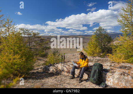 Backpacker reading map on forest trip while resting. Stock Photo