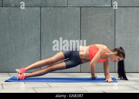 Fit young woman doing sideplanks, strengthening her core, working out on a mat, lifestyle and health concept Stock Photo