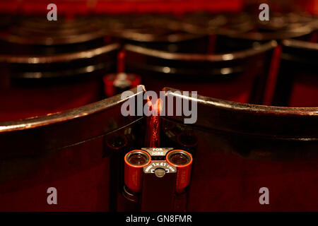 opera glasses for hire on back of a row of seats in the stalls of an old style theatre Stock Photo