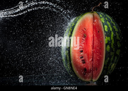 Watermelon on a black background. Water in motion. A series of fruits and vegetables in motion. Stock Photo