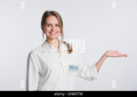 Young doctor woman nurse presenting and showing copy space for product or text. Caucasian female medical professional isolated on white background. Stock Photo