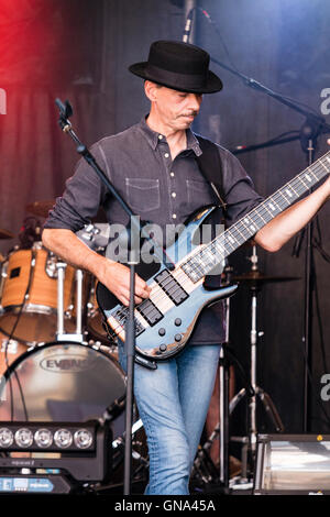 England. Caucasian man, Nigel Hardstone, wearing black hat, sanding on stage playing bass guitar during a concert by rock group Paragraph 1. Close up. Stock Photo