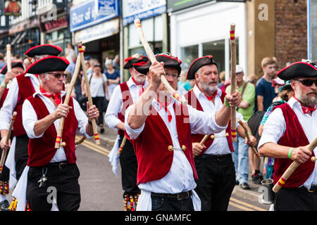 Traditional English folk dancers, Victory Morris, wearing 18th century sailor costumes, dancing as they march through town street during parade. Stock Photo