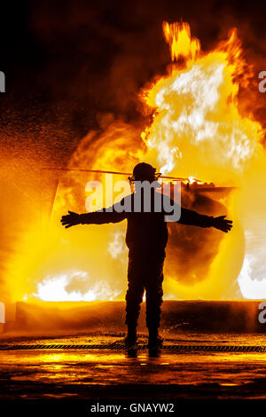 Firechief with arms open in front of fire Stock Photo
