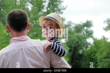 Young boy with face painted being held by his father at a concert. Stock Photo