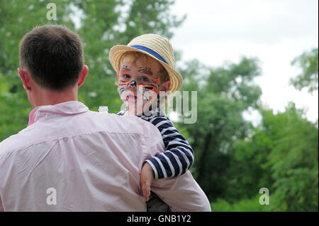 Young boy with face painted being held by his father at a concert. Stock Photo