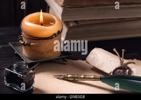 Letter with quil pen and lighted candle Stock Photo