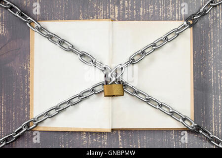 Open book with chain and padlock on wooden background. Stock Photo