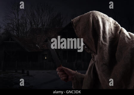 The hooded man with a big knife Stock Photo